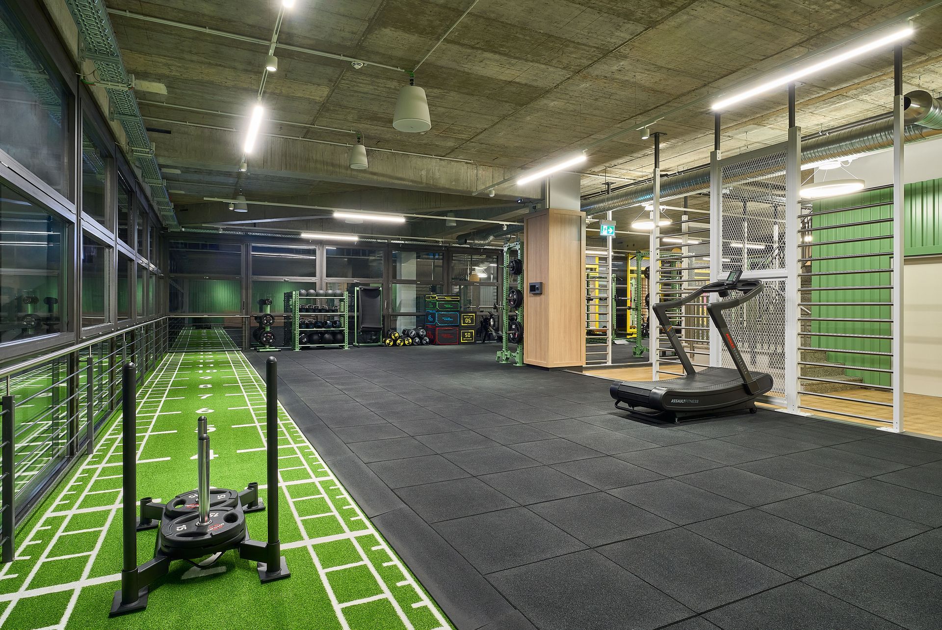 Innenausbau Fitnessstudio McFIT München Forstenried - Funktioneller Trainingsbereich im Fitnessstudio mit Kunstrasen-Sektion, Hantelbereich, einem Laufband und freistehenden Geräten - Referenzprojekt Fitnessstudio Innenausbau Generalunternehmer