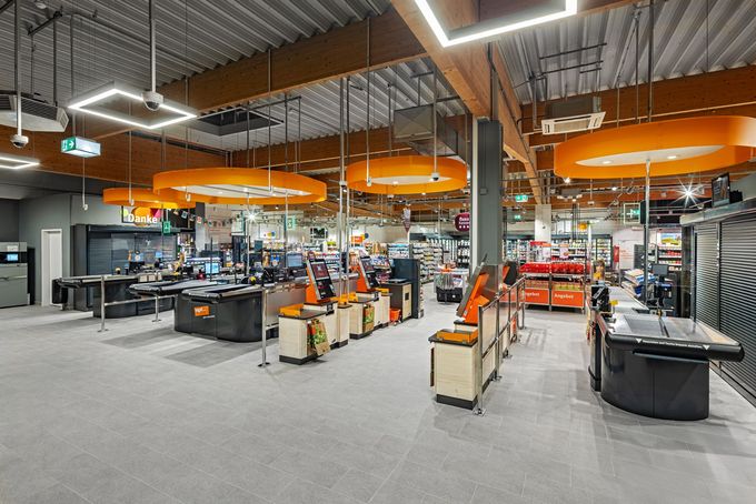 Innenausbau-Projekt Einzelhandel Ladenbau tegut, Witzenhausen - Geräumiger Supermarkt mit Selbstbedienungskassen, traditionellen Kassen & heller Beleuchtung. Orange Akzente dominieren - Referenzprojekt Retail Innenausbau Generalunternehmer