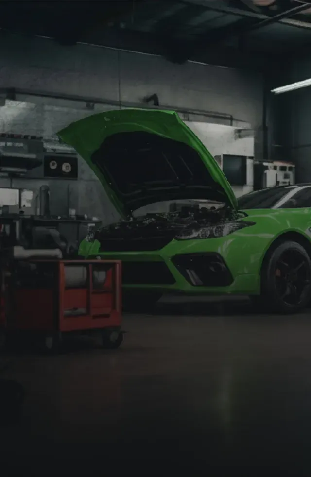 Green car parked in garage with hood up | Manassas Auto & Tire