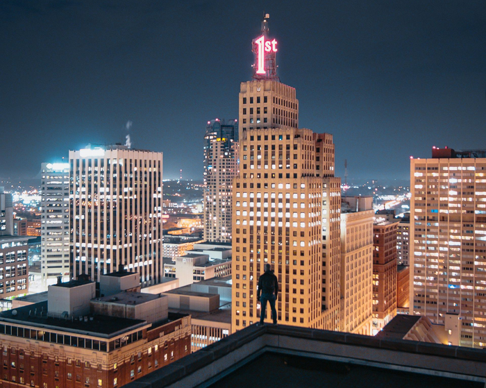 Person on rooftop overlooking St. Paul, MN. Tall buildings with lit windows, including 1st Bank Tower