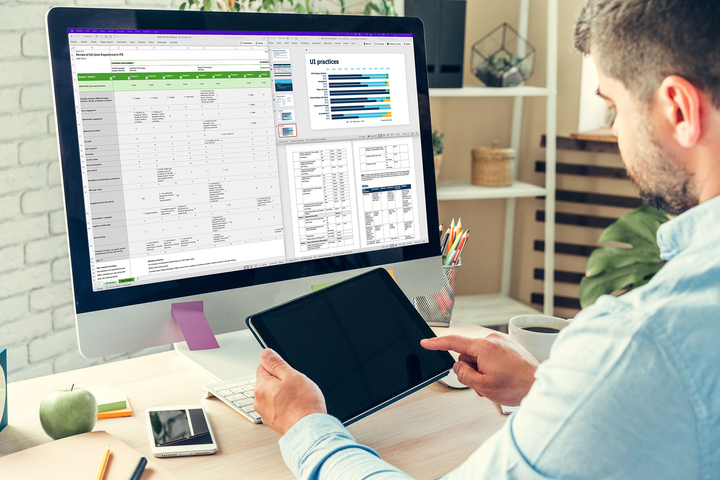 A man is sitting at a desk using a tablet and a computer to review the results of the internal UX review.