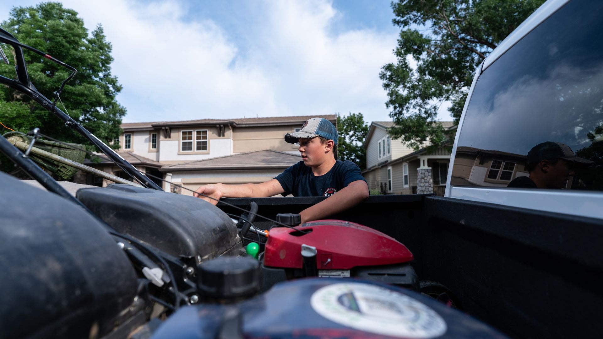 Halftime Help student-athlete crew member preparing equipment in truck bed before lawn care service in south Denver metro