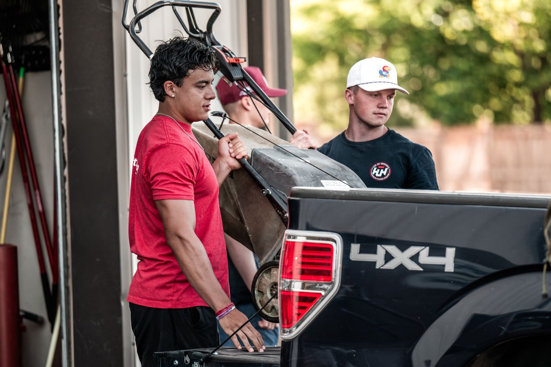 Halftime Help student-athlete team putting the lawn mower on the back of the truck  in the South Denver metro area.