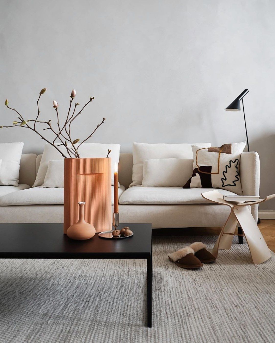 Un living cu o canapea albă și o măsuță de cafea neagră.