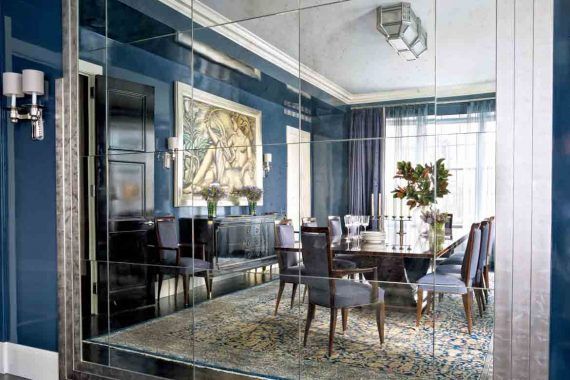 O sufragerie cu peretii albastri si o oglinda mare pe perete.