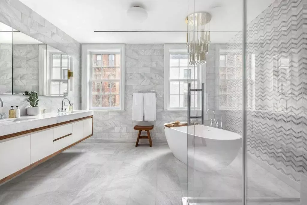 O baie cu cadă, chiuvete, oglinzi și cabină de duș.