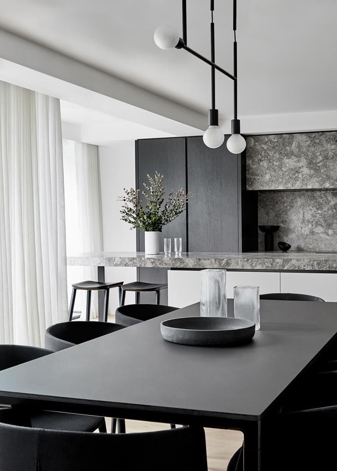 O sufragerie cu o masă și scaune și o bucătărie în fundal.