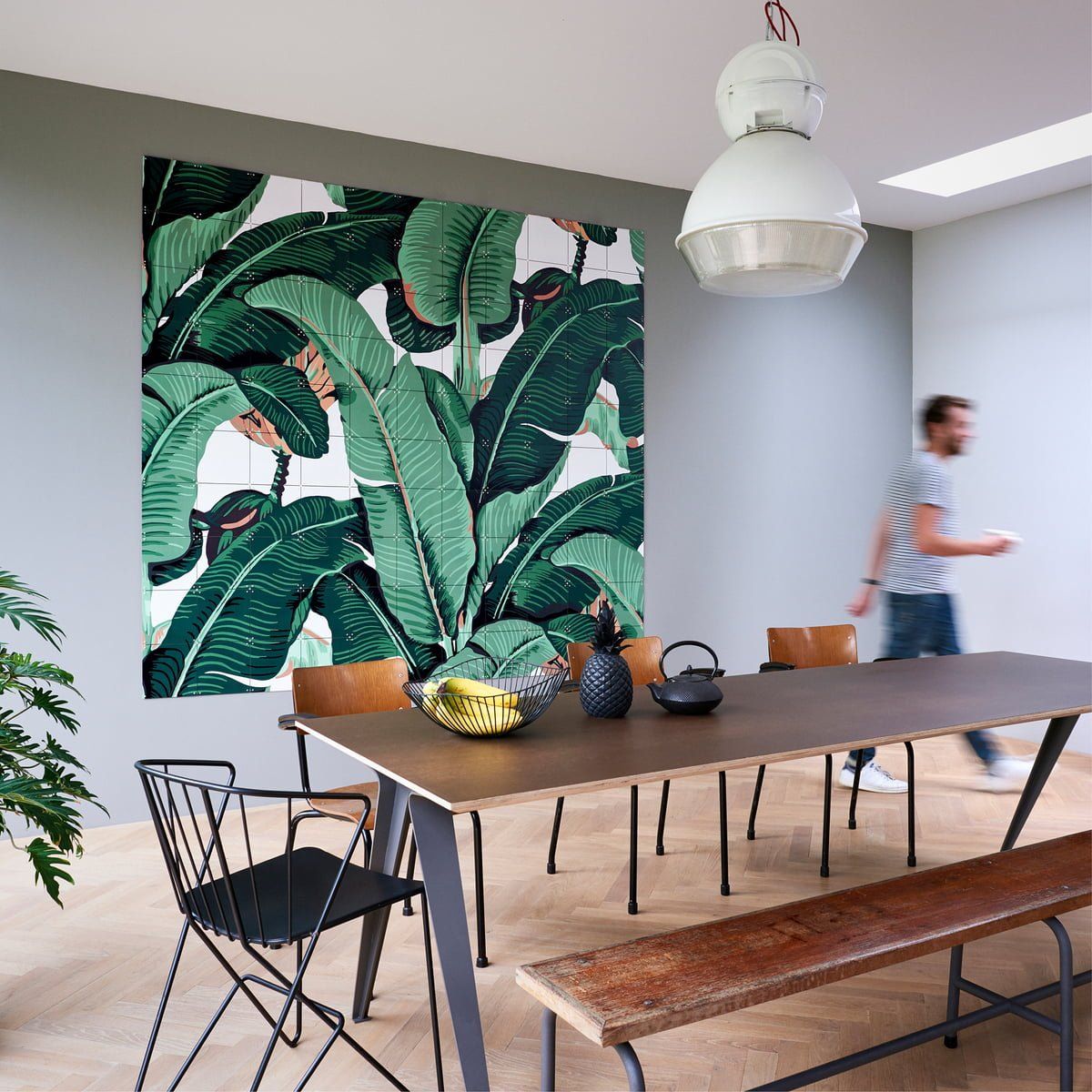 Un bărbat se plimbă într-o sufragerie cu masă și scaune.