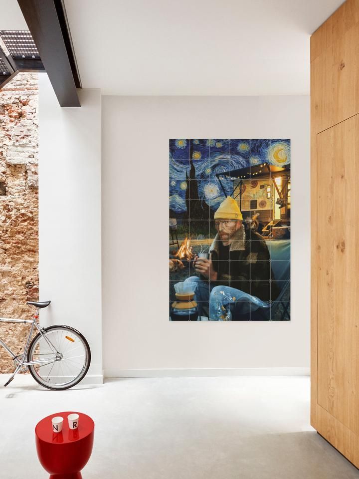 Un tablou cu Vincent van Gogh este atârnat pe un perete lângă o bicicletă.