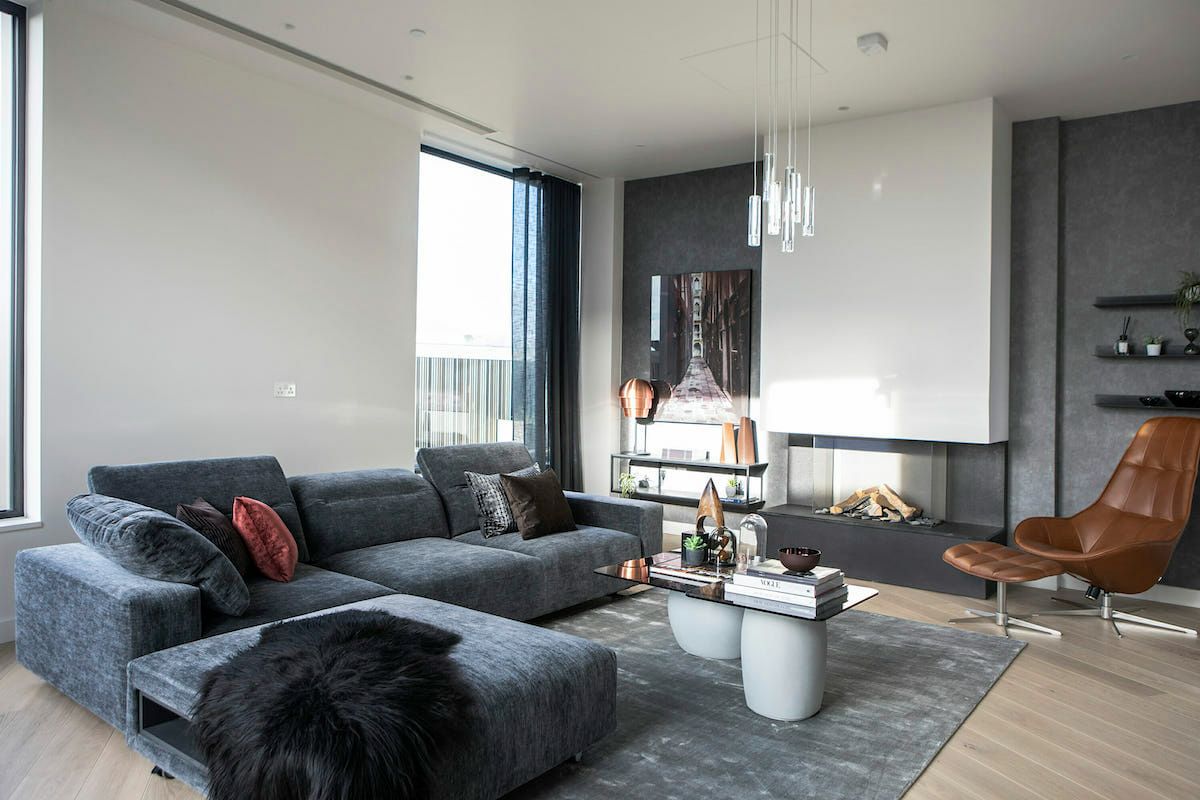 Un living cu o canapea , scaun , masuta de cafea si semineu.