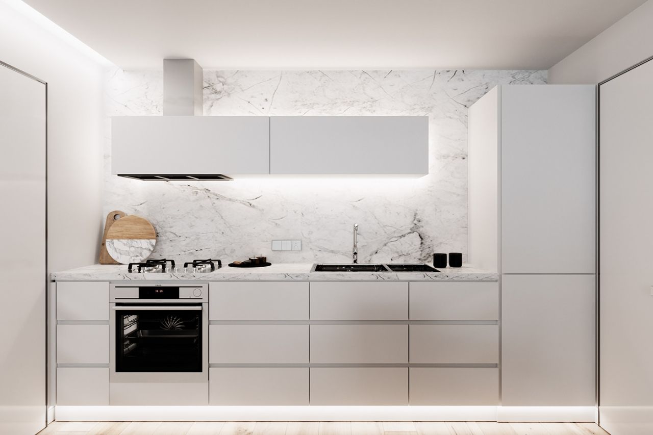 O bucătărie cu dulapuri albe, un aragaz, o chiuvetă și un frigider.