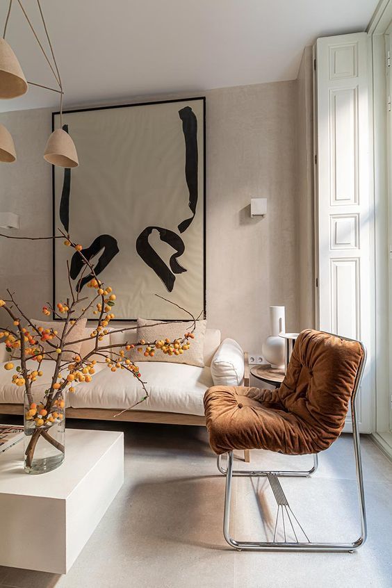 Un living cu o canapea , scaun , masuta de cafea si un tablou mare pe perete.