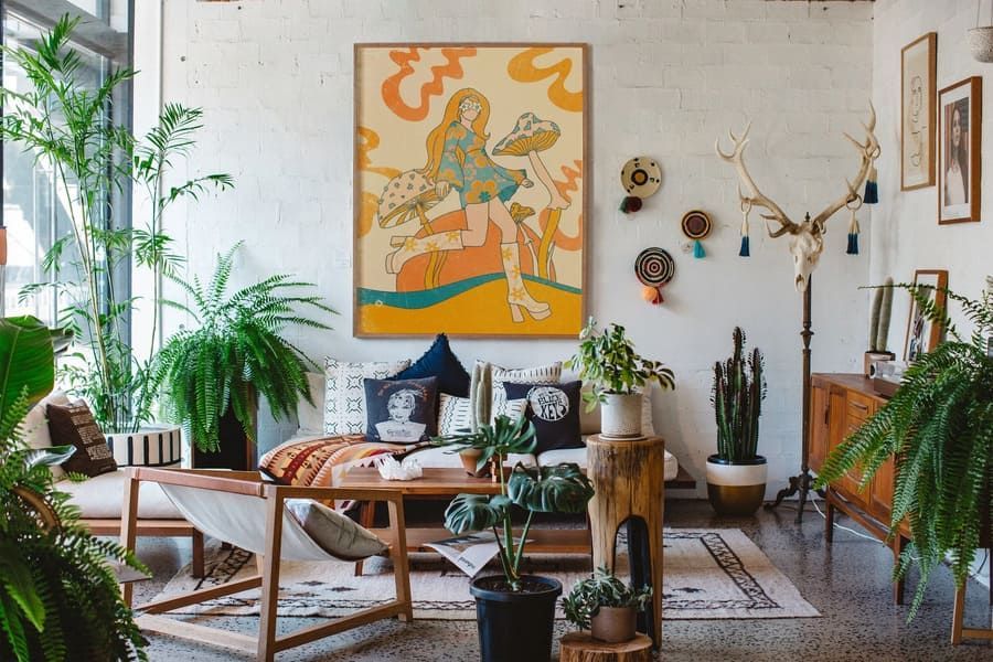 O sufragerie plina cu mobilier si plante si un tablou pe perete.