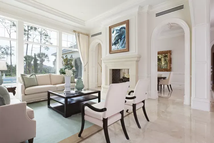 Un living cu o canapea , scaune , masuta de cafea si semineu.