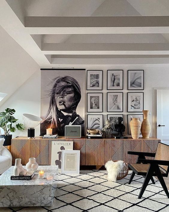 Un living cu o masuta de cafea din marmura , scaune , vaze si un tablou pe perete.