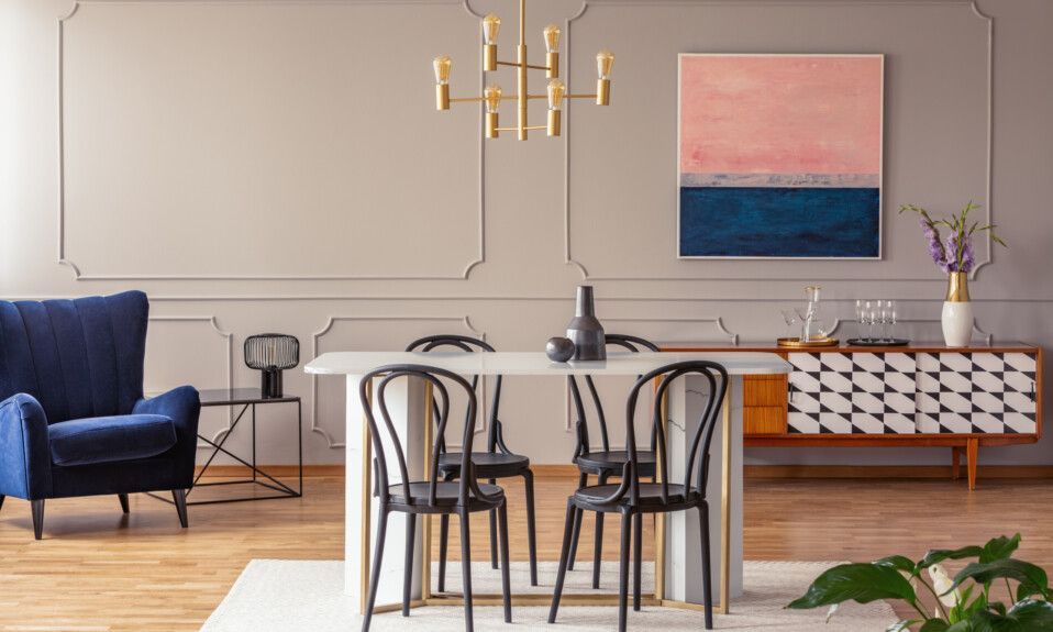 O sufragerie cu o masa , scaune , un scaun albastru si un tablou pe perete.