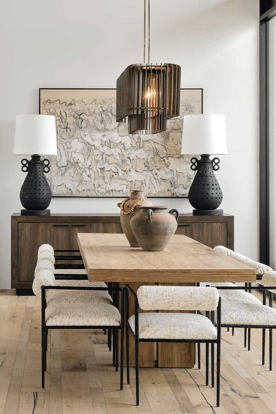 O sufragerie cu o masa si scaune din lemn si doua lampi.