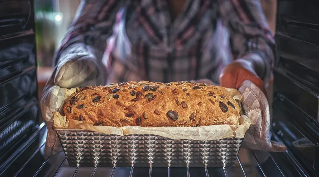 O persoană scoate o pâine din cuptor.