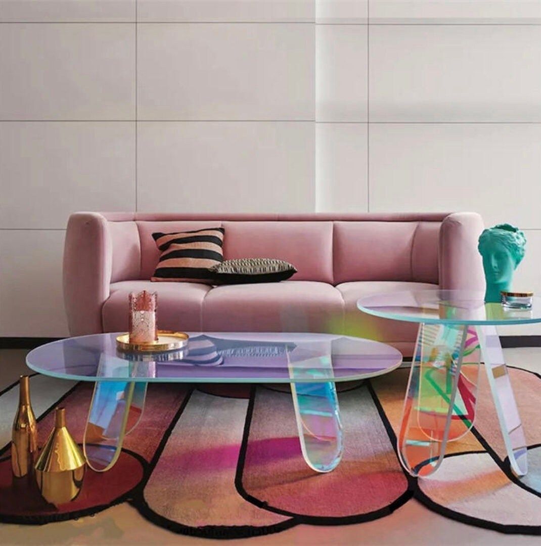 Un living cu o canapea roz și două mese