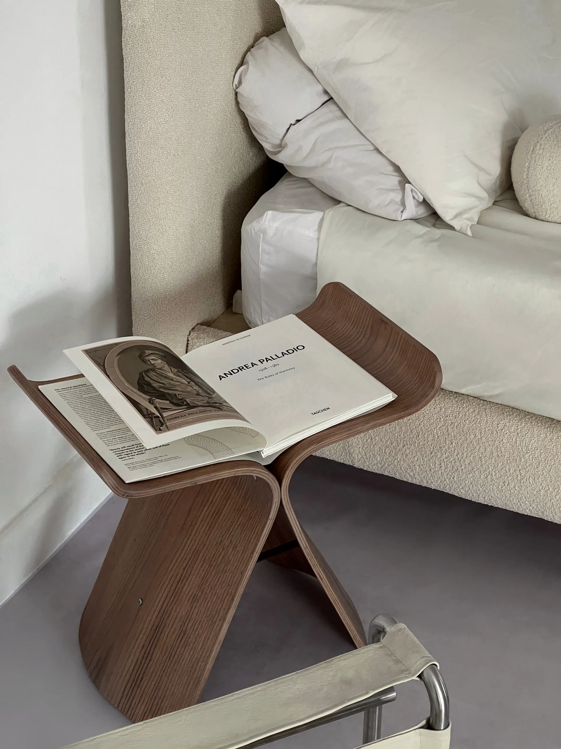 O carte stă pe o masă de lemn lângă un pat.