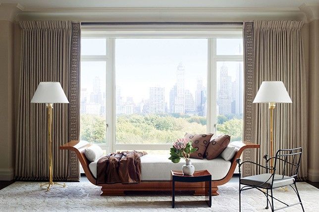 Un living cu o canapea, scaun, lămpi și o fereastră mare.