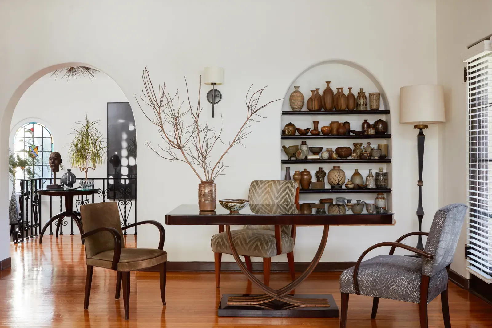 O sufragerie cu o masă și scaune și un raft cu vaze pe ea