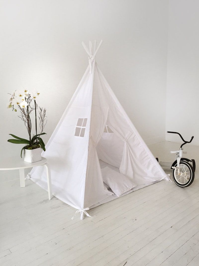 Un tipi alb stă pe o podea albă lângă o tricicletă.