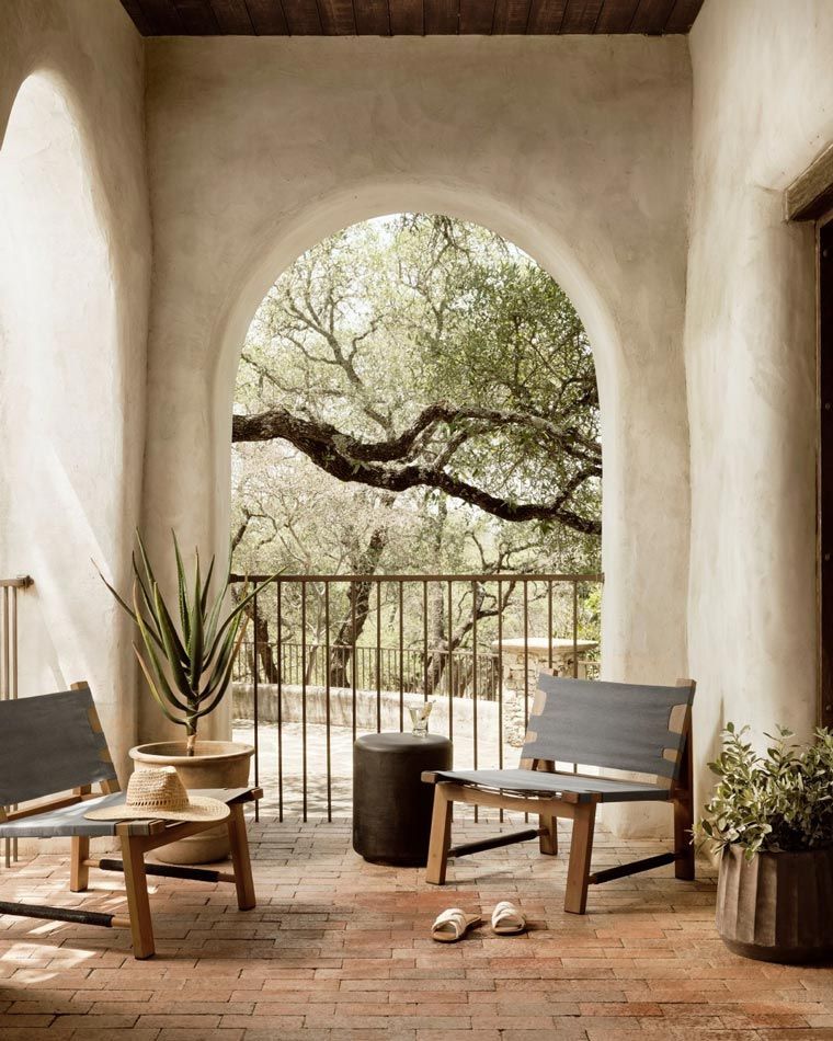 Un balcon cu două scaune și o masă cu vedere la copaci.