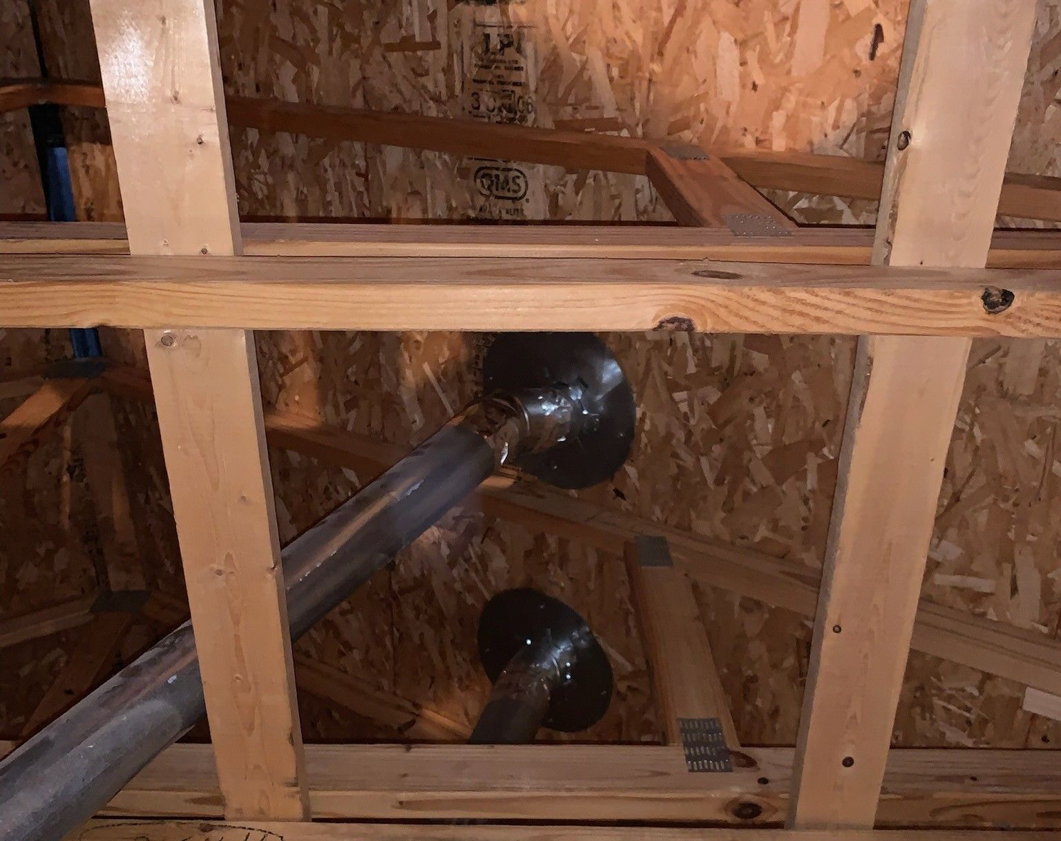 Attic with wooden beams, air ducts, and exposed plywood.