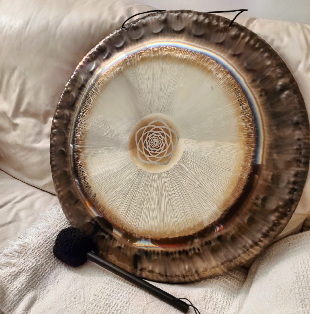 Persona limpiando un gong grande con diseño de flor de loto.