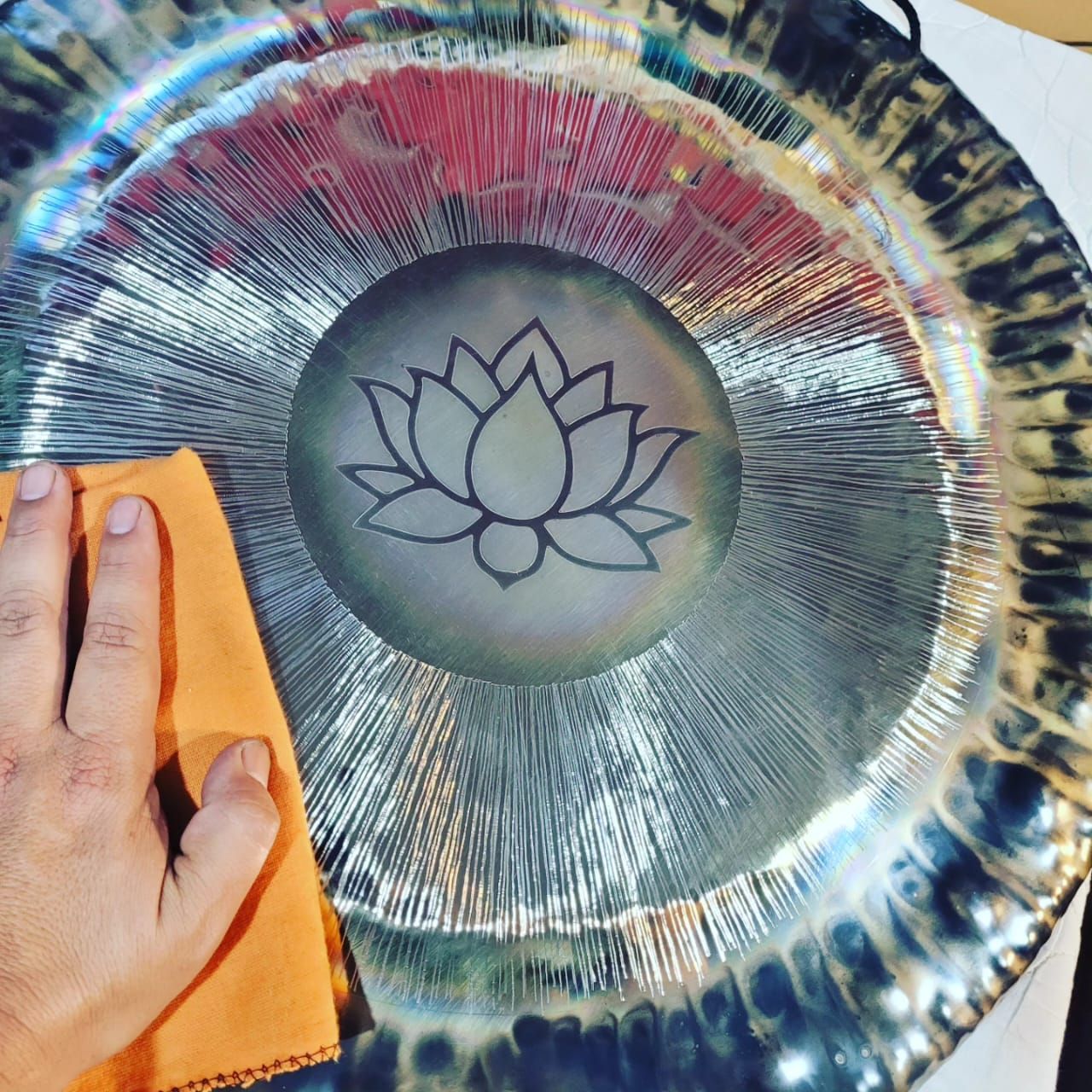 Persona puliendo un gong grande con diseño de flor de loto.