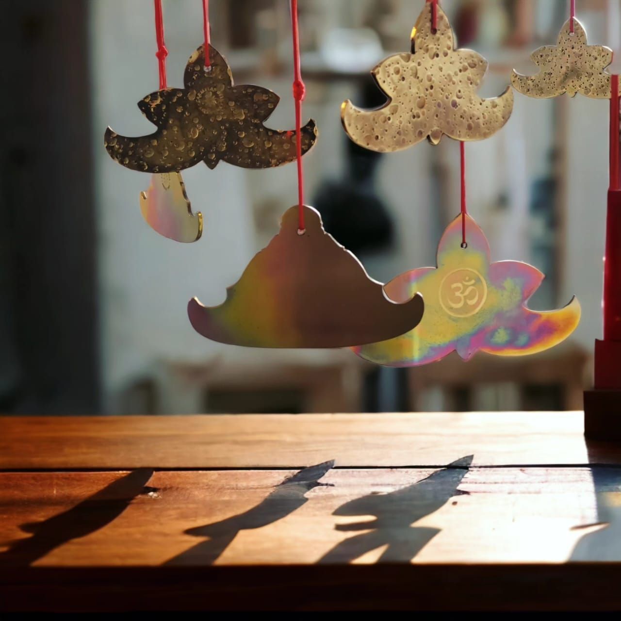 Campanas metálicas ornamentales colgantes, proyectando sombras sobre una superficie de madera, con un fondo borroso.