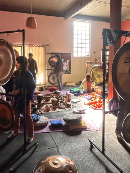 Un estudio de baño de sonido con gongs, instrumentos y personas preparándose para una sesión.