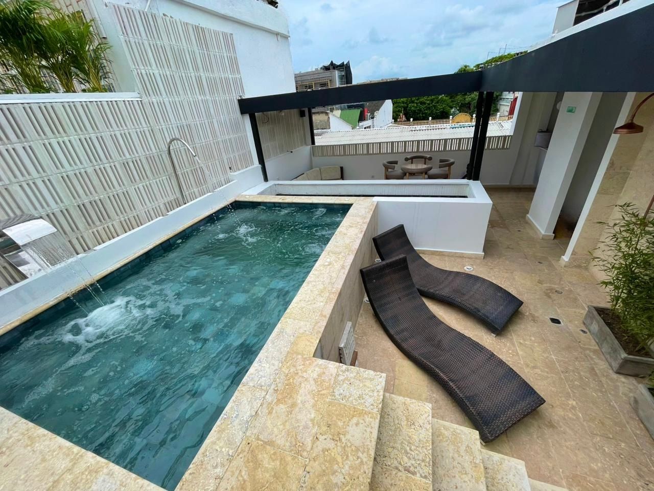 Rooftop pool area with a small pool, lounge chairs, and a covered seating area.