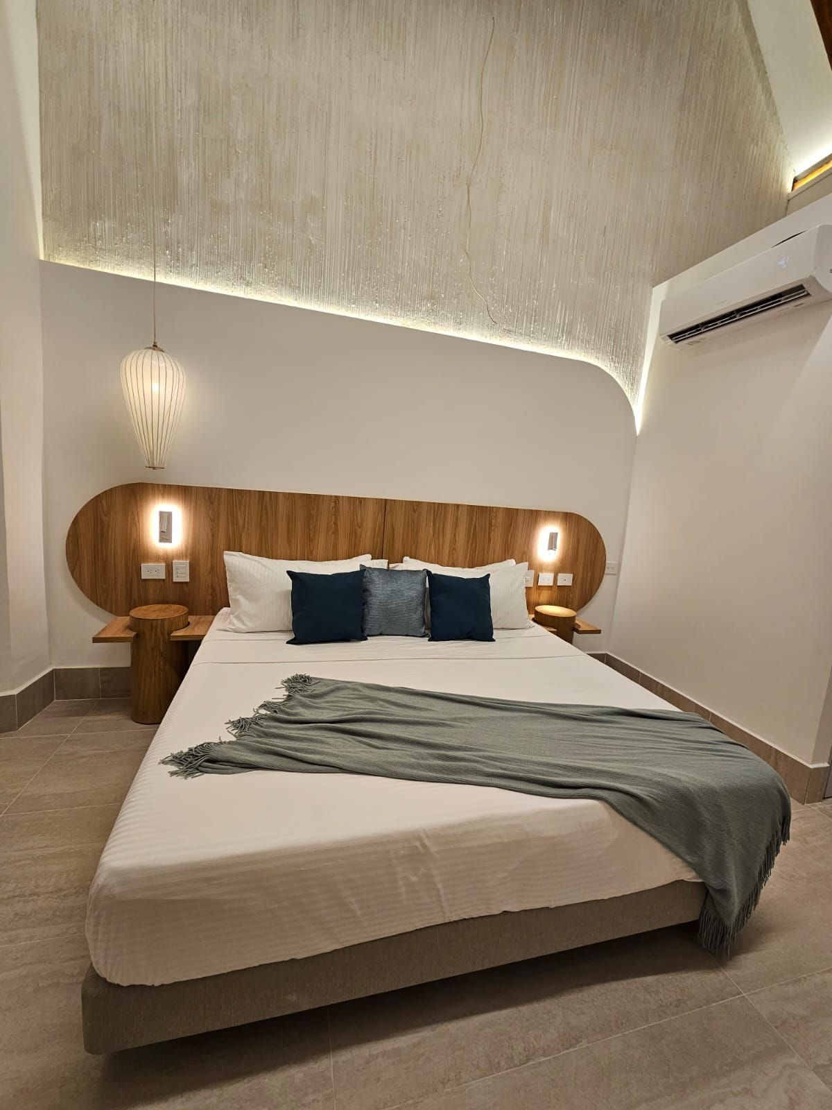 Bedroom with wooden headboard, bed with blue pillows and a green blanket, and a textured ceiling.