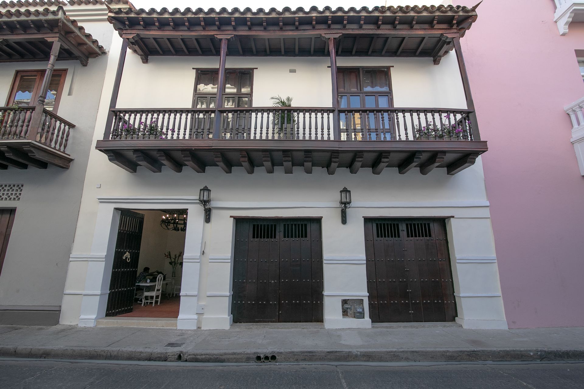 A white building with a balcony and two garage doors