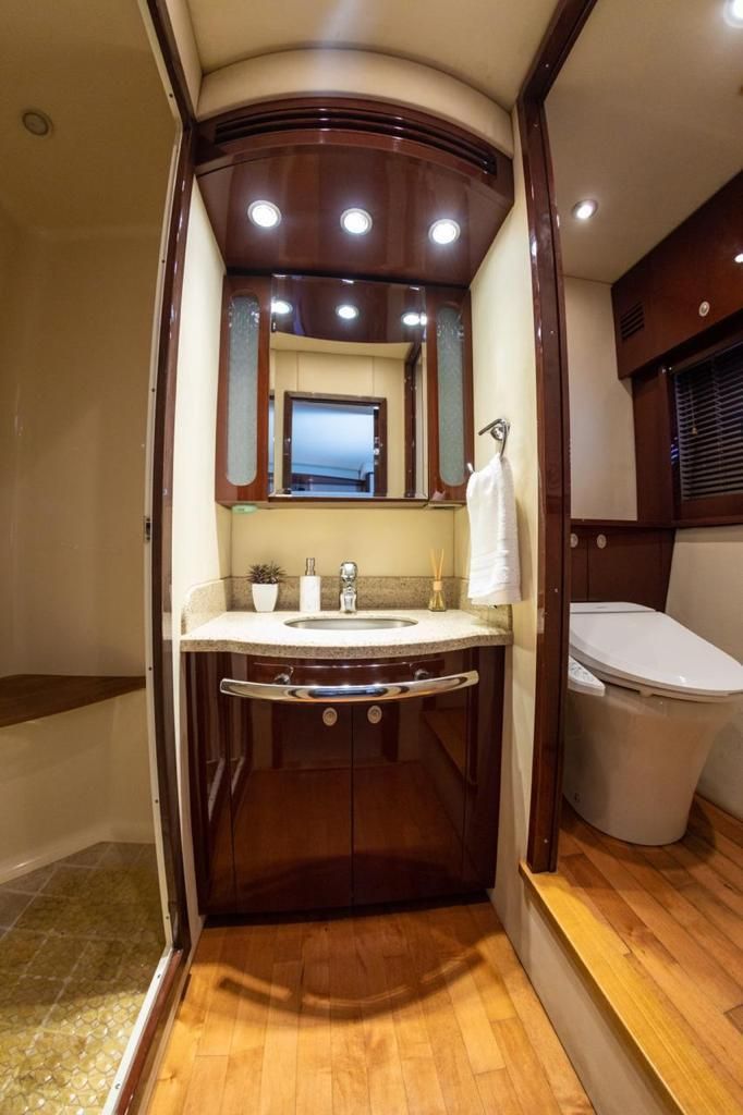 Bathroom with dark wood cabinetry, a sink, toilet, and shower. Neutral walls and light wood flooring.