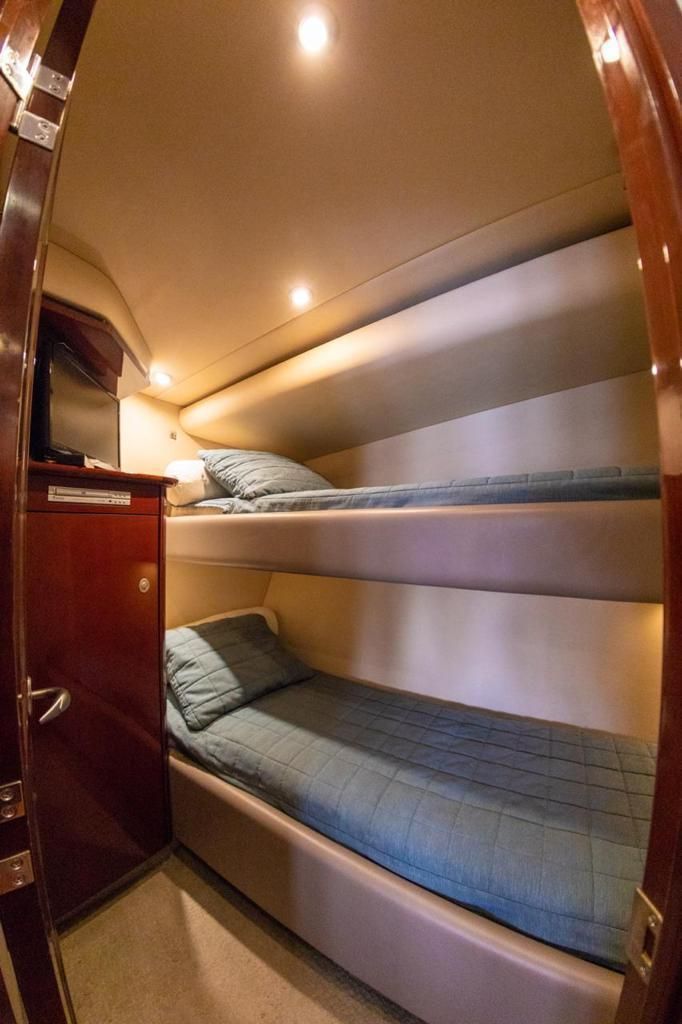 Bunk beds in a boat cabin with teal bedding and wood paneling.
