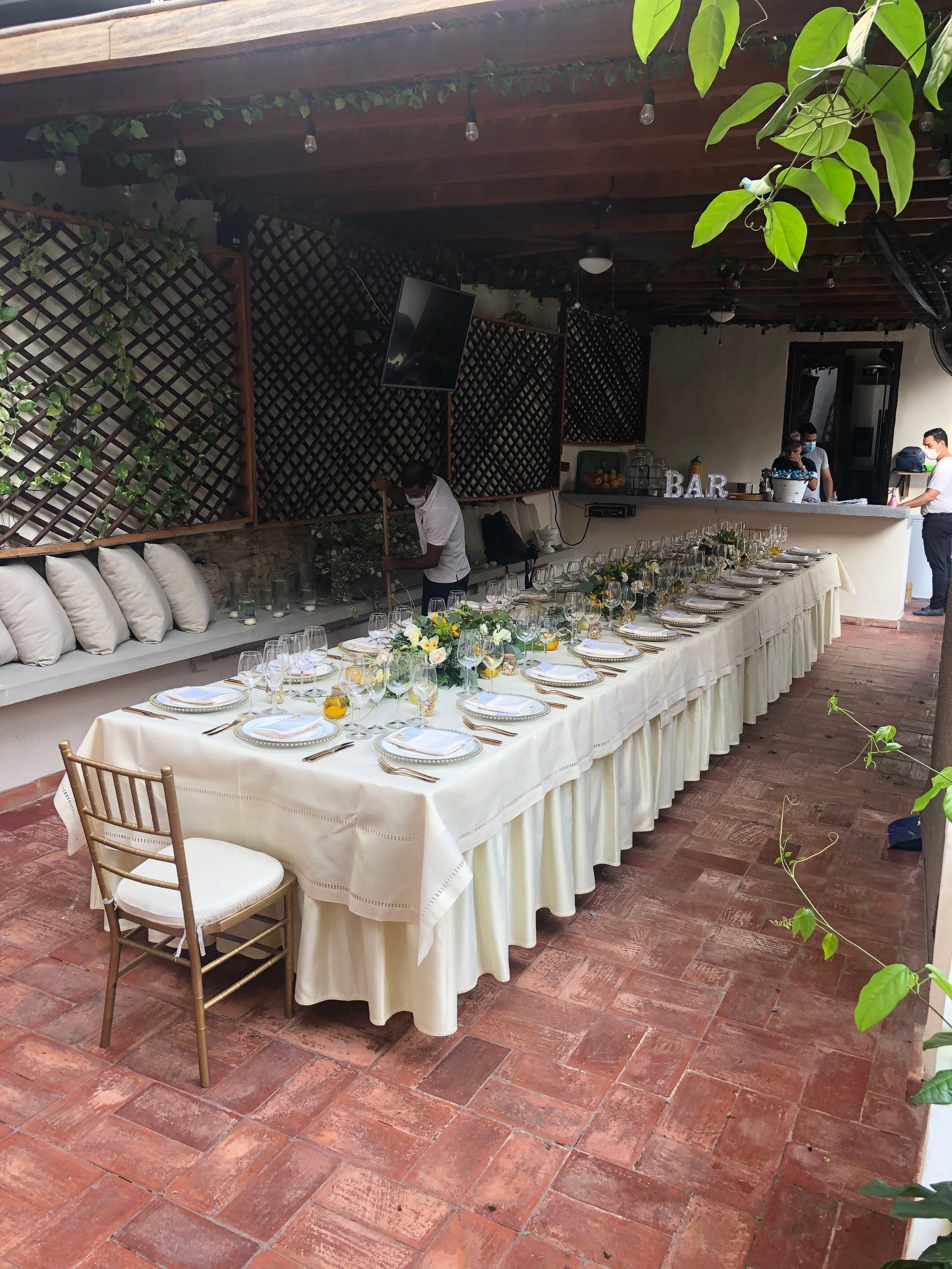 A long table with a white tablecloth and chairs on a patio.