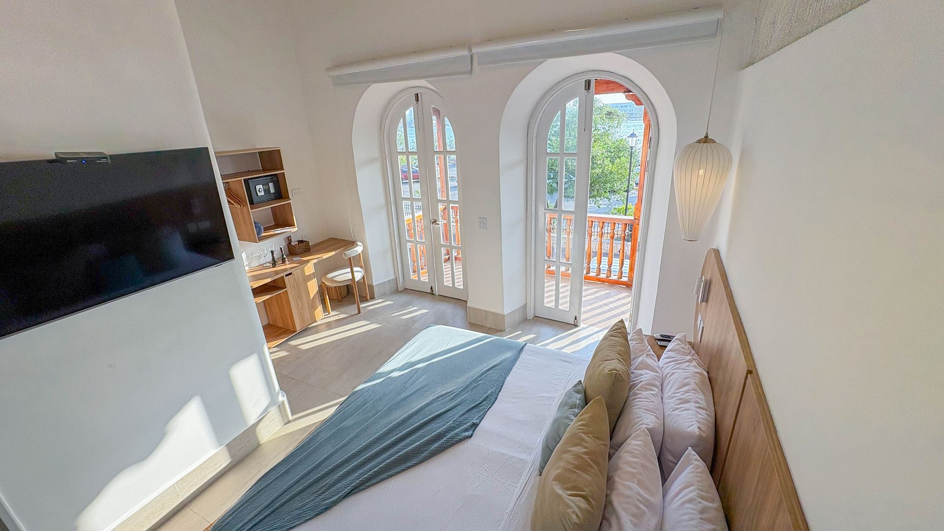 Bedroom with a king-size bed, desk, and French doors leading to a balcony with a view.