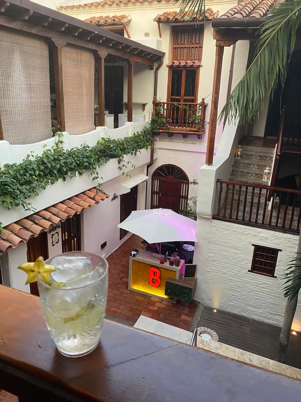 A glass of water with a star on it is on a balcony overlooking a courtyard.