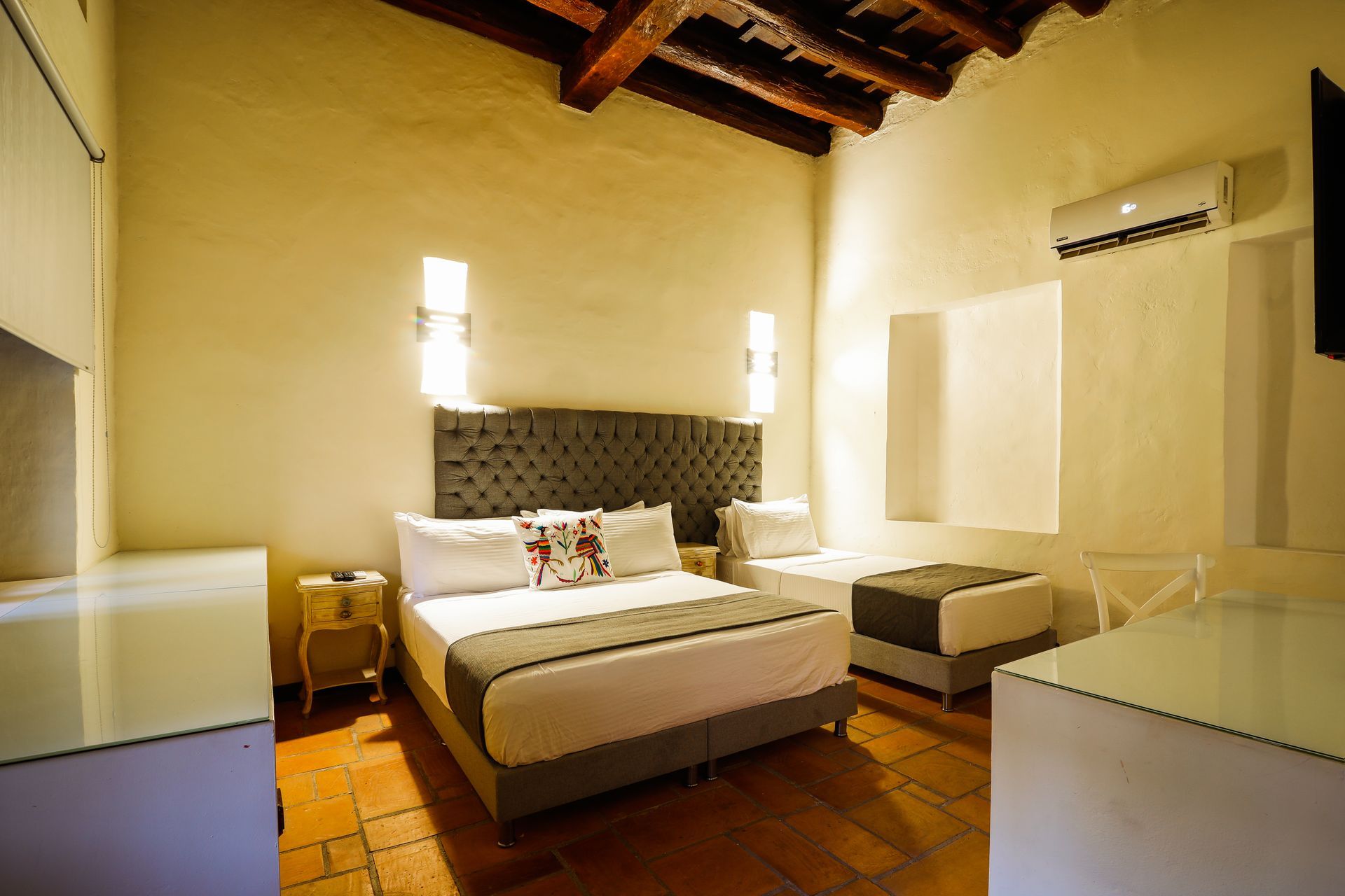 A hotel room with a large bed and two smaller beds.