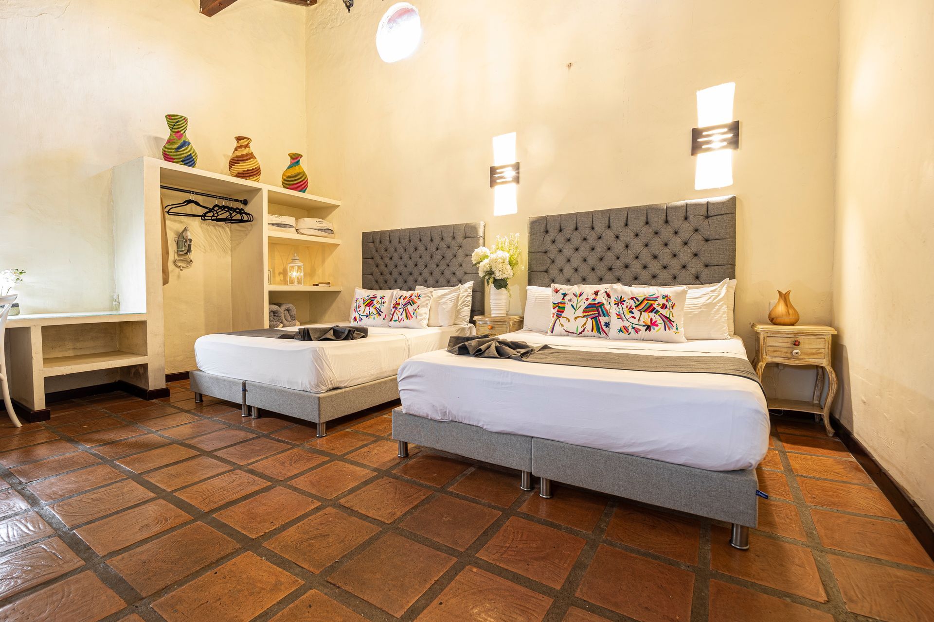 A hotel room with two beds and a tiled floor.