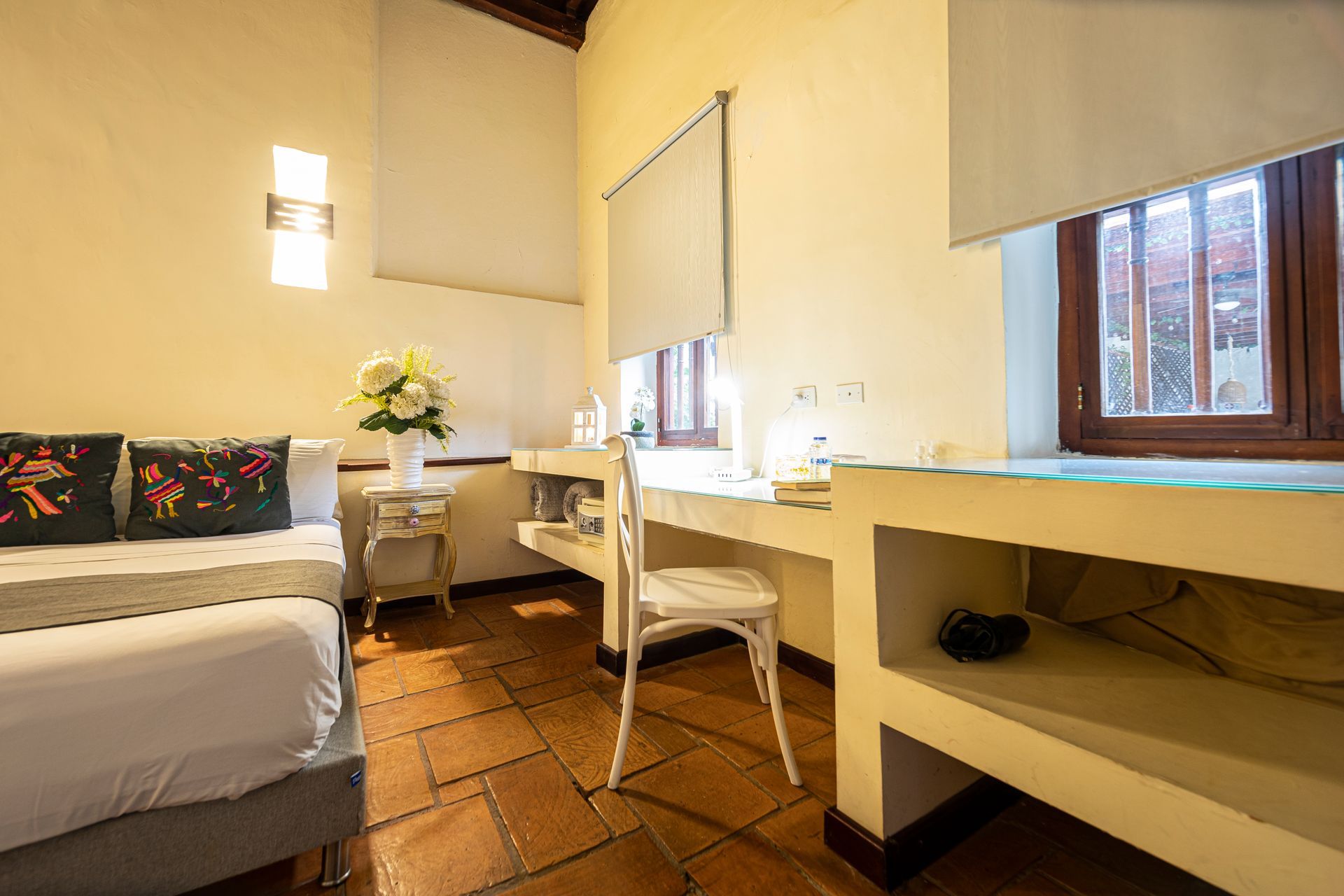 A hotel room with a bed , desk , chair and window.