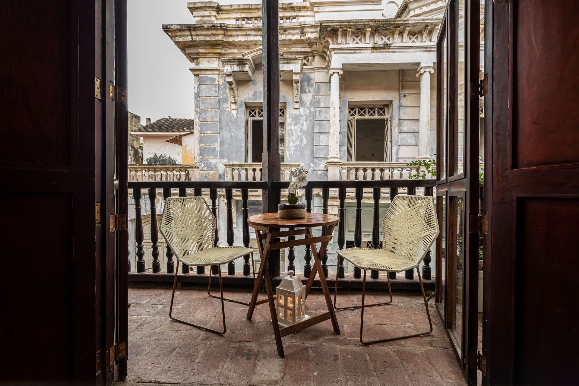 A balcony with two chairs and a table with a view of a building.