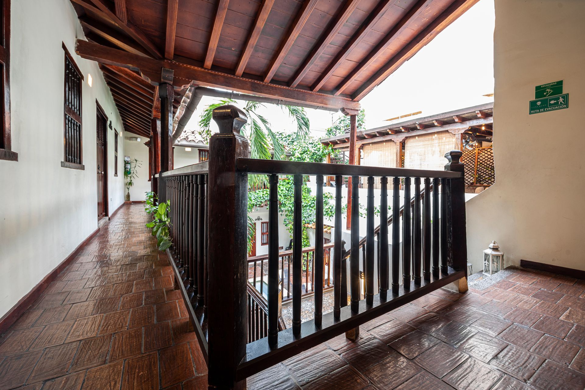 A long hallway with a wooden railing and a green exit sign