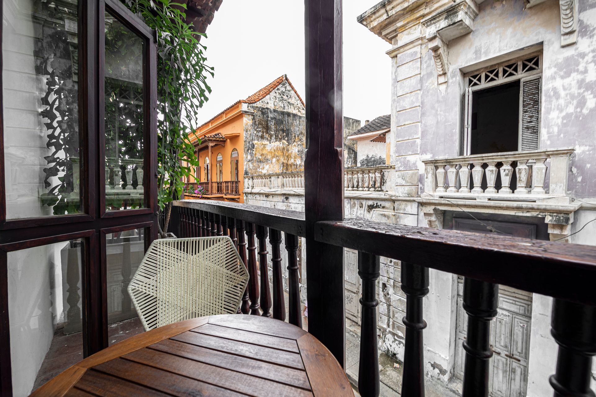 A balcony with a wooden table and chairs and a view of a city.
