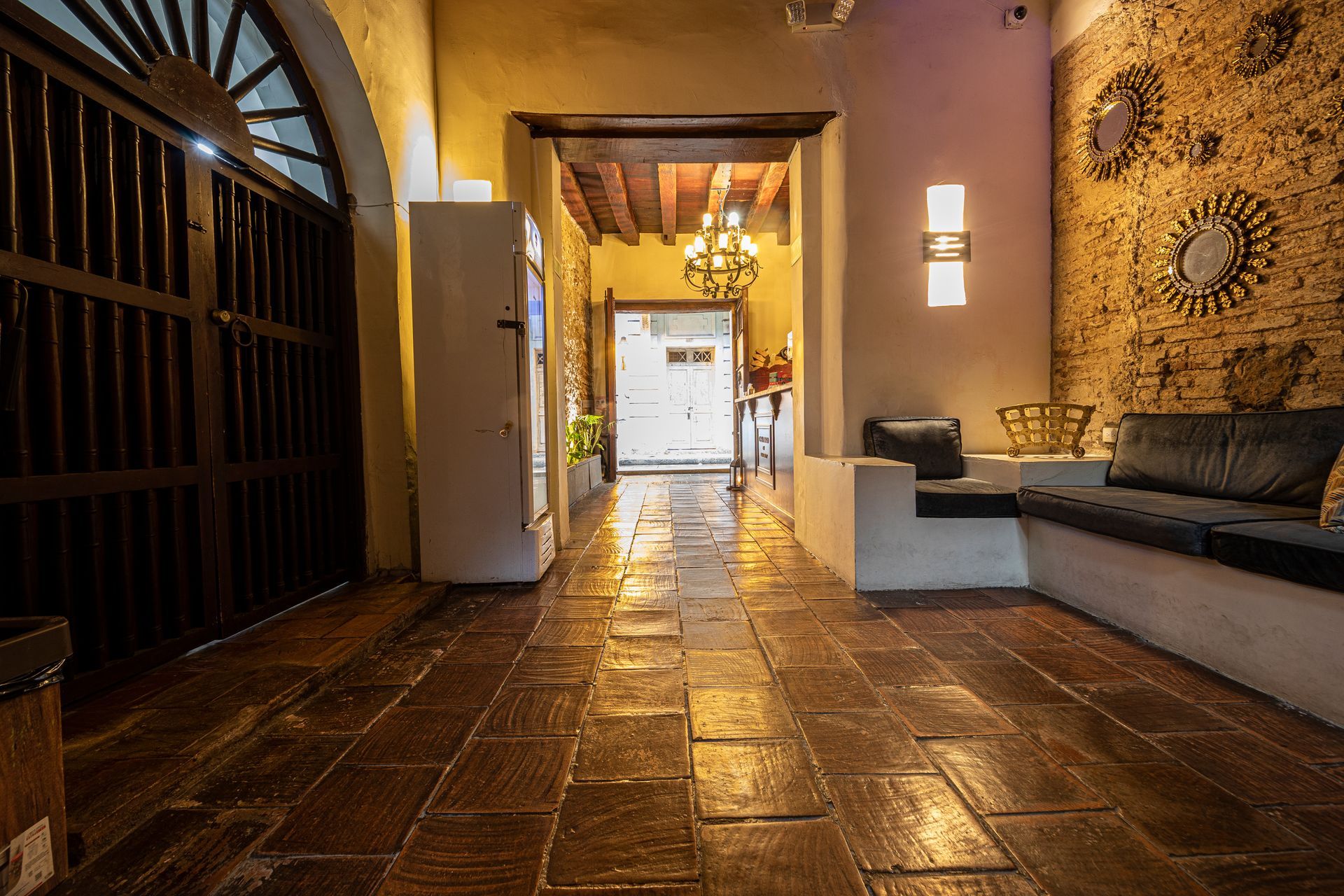 A long hallway with a brick floor and a couch.