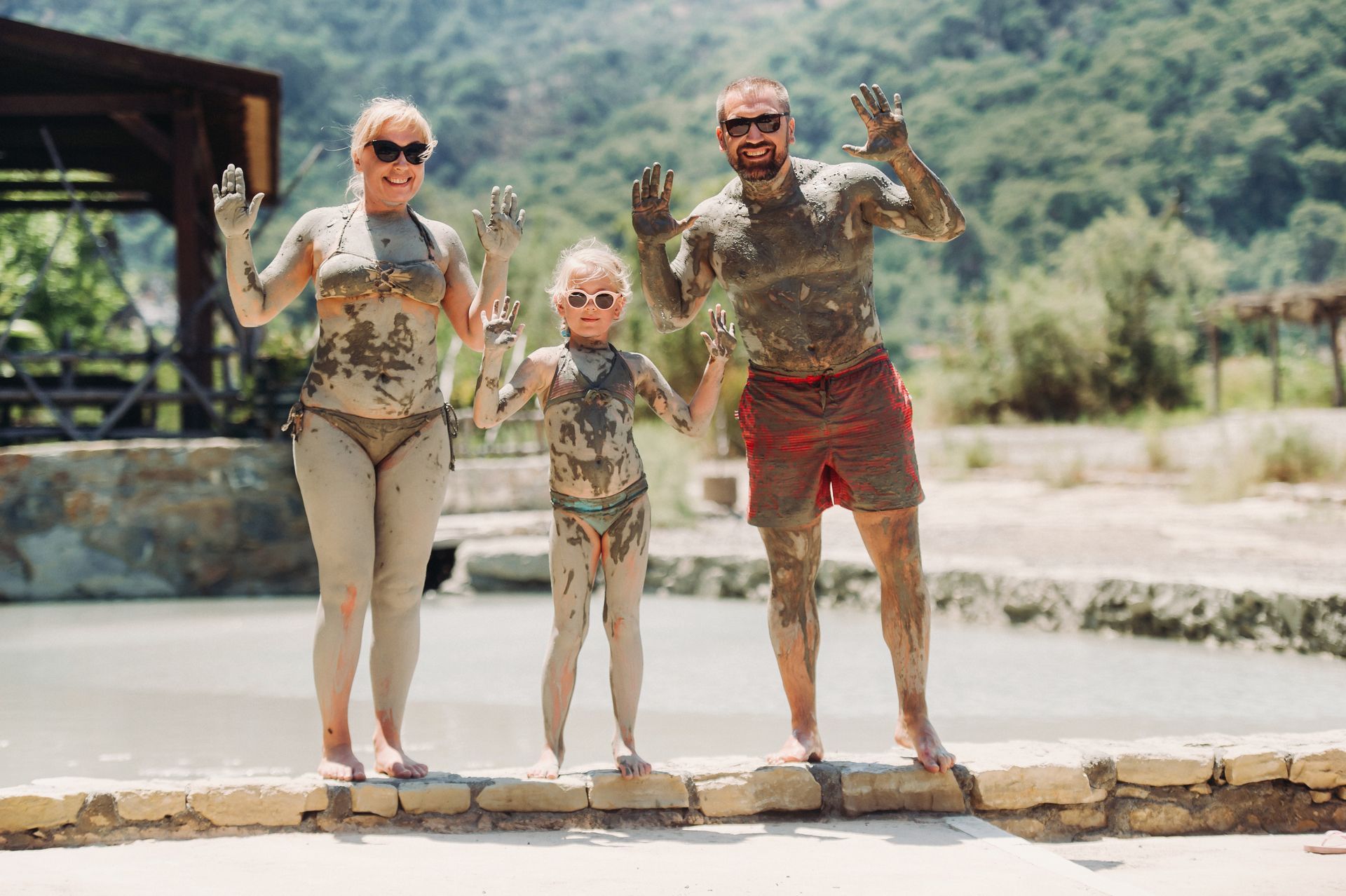 A family covered in mud is standing next to each other on a sidewalk.