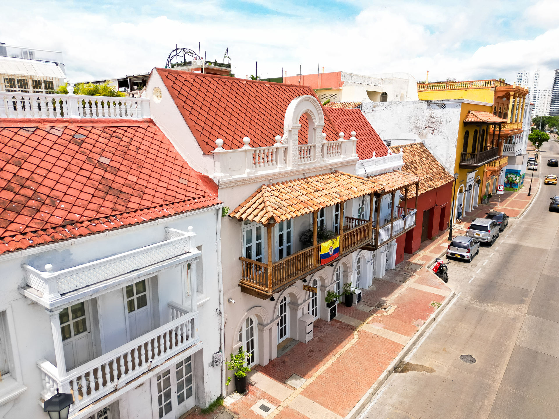 Row of colorful buildings in Cartagena, Colombia, with red tile roofs and balconies along a sunny street.